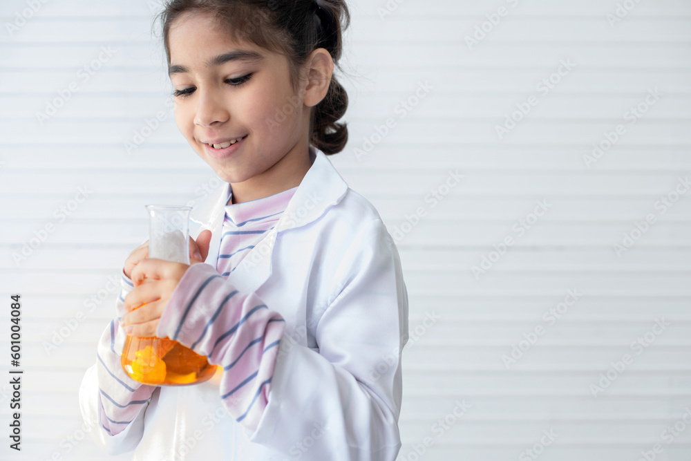 Asian school girl holding yellow liquid in beaker on white wall, learning chemistry in laboratory at school Asian school girl holding yellow liquid in beaker on white wall, learning chemistry in laboratory at school