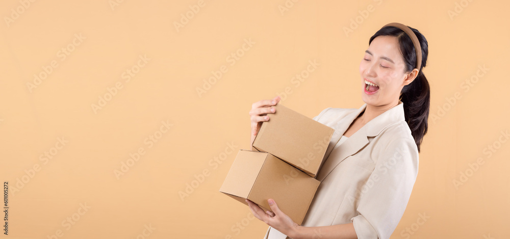 portrait of happy successful confident young asian business woman wearing white jacket holding parcel box isolated on beige studio background, Delivery courier and shipping service concept. portrait of happy successful confident young asian business woman wearing white jacket holding parcel box isolated on beige studio background, Delivery courier and shipping service concept.