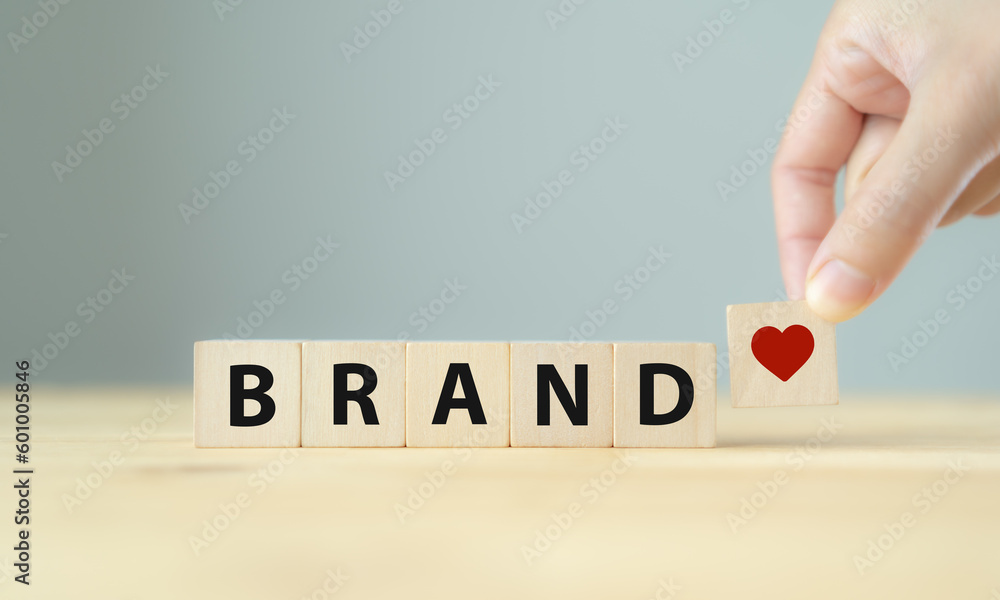 Build brand loyalty concept. Customers continue engaging and purchasing from the same brand, positive feelings toward brand. Wooden cube blocks with BRAND text and red heart icon on clean background.. - obrazy, fototapety, plakaty 