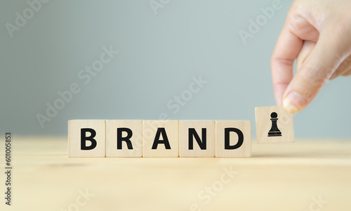 Brand strategy concept. Developing a strong brand strategy differentiate from competitors and build loyalty with customers. Wooden cube blocks with BRAND text and strategy icon on clean background.