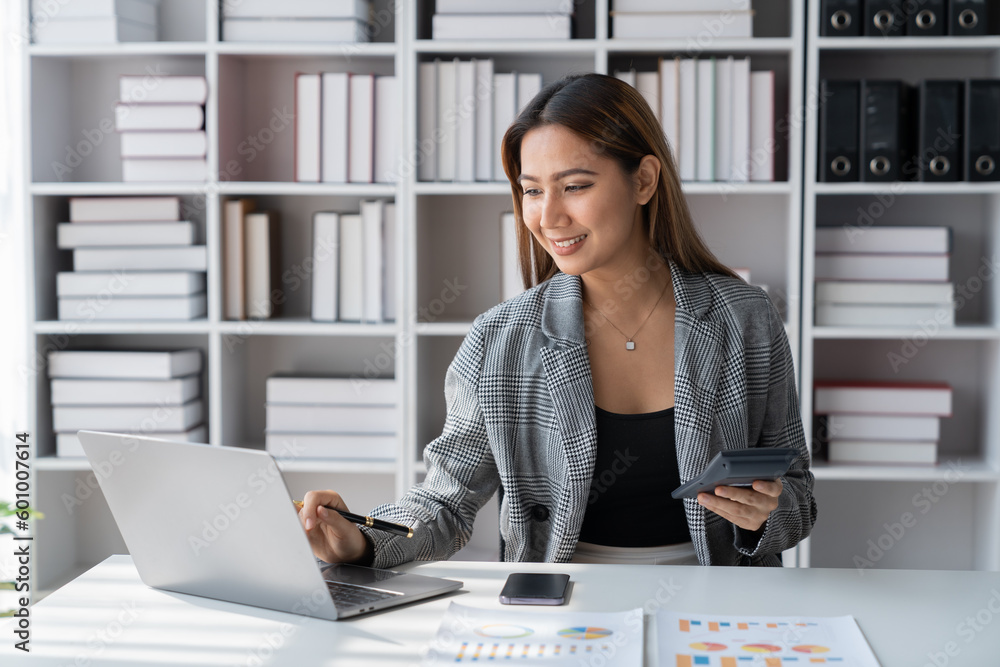 Asian businesswoman using calculator to do financial business calculations Investment with data graph document. Statistics. Laptop computer at office. lifestyle management concept. Asian businesswoman using calculator to do financial business calculations Investment with data graph document. Statistics. Laptop computer at office. lifestyle management concept.