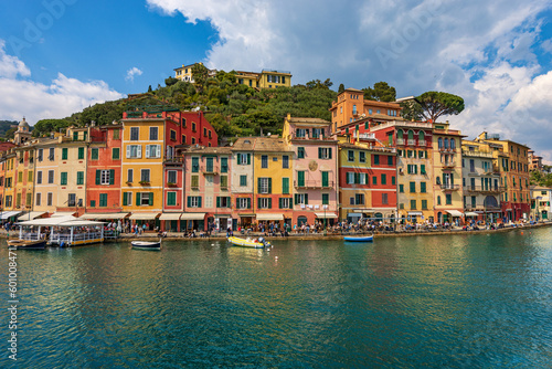 Multi coloured houses and port of Portofino, luxury tourist resort in Genoa Province, Liguria, Italy, Europe. Waterfront and promenade with many tourists on a sunny spring day. Mediterranean sea.