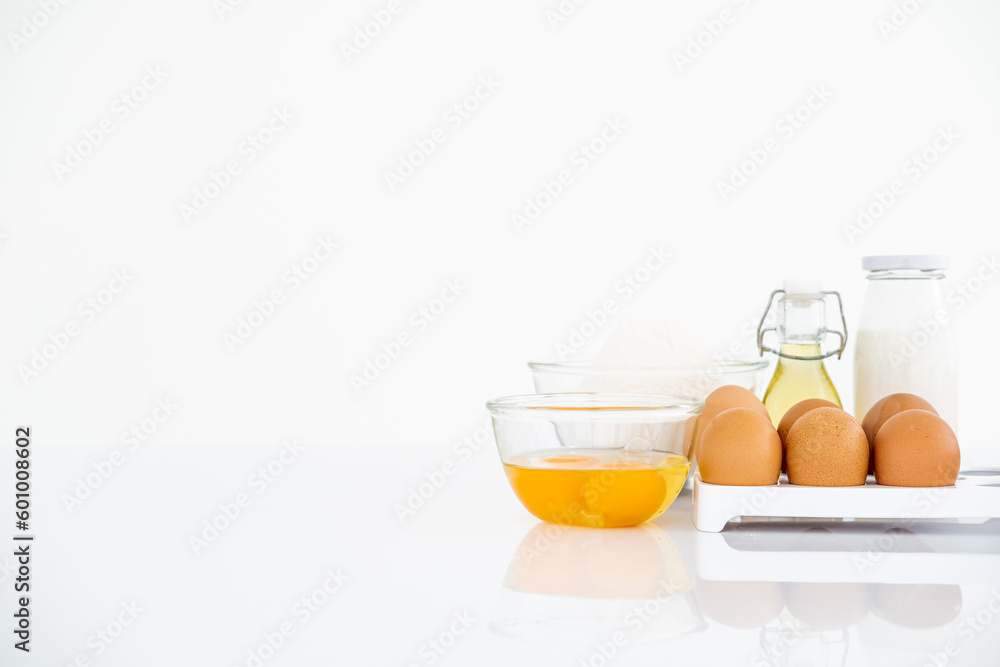 Wheat flour with eggs, oil and milk on table . White table Front view copyspace Wheat flour with eggs, oil and milk on table . White table Front view copyspace