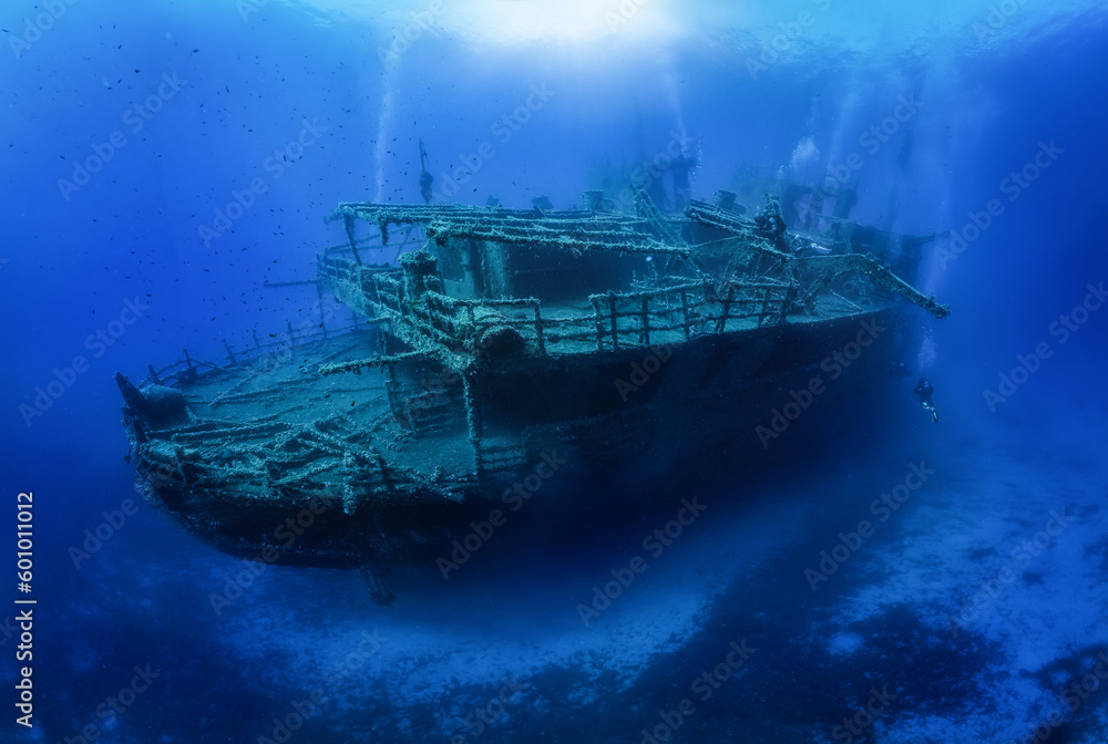 A group of unrecognizable divers explore a sunken shipwreck in the blue, mediterranean sea at Naxos island, Greece A group of unrecognizable divers explore a sunken shipwreck in the blue, mediterranean sea at Naxos island, Greece