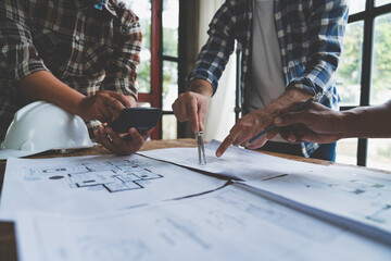 Meeting of plans and calculations on house plan drawings of engineers, architects on blue print with equipment discussing at desk. Teamwork and management concept. Construction