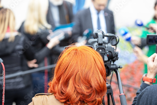 Female camera operator at work during live news conference or media event filming with video camera