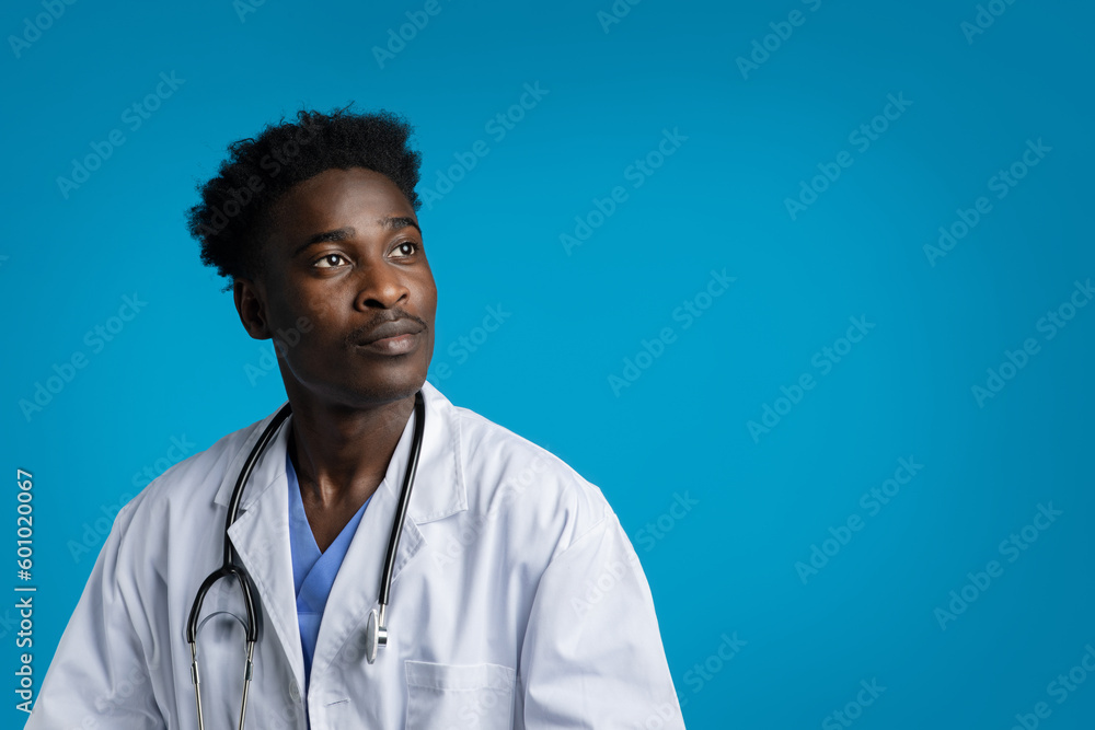Interested black doctor looking at copy space on blue Interested black doctor looking at copy space on blue