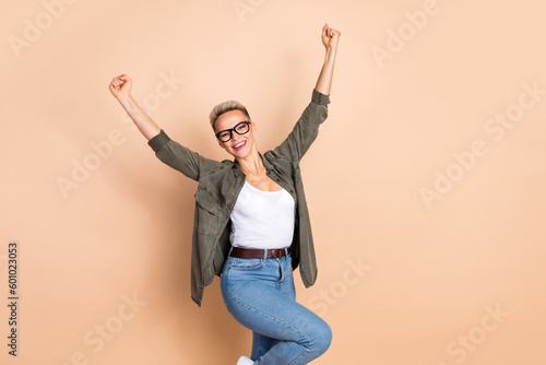 Portrait of delighted funny person raise fists triumph luck empty space isolated on beige color background