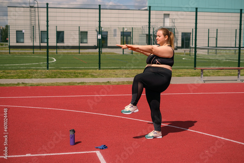 A fat obese woman does fitness exercises by lifting her knees up. Attempts to lose weight