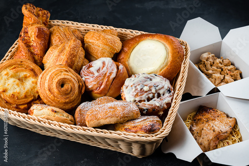 Fresh pastries: croissants, rolls, puffs and bun with sour cream with chicken and pasta in paper boxes.