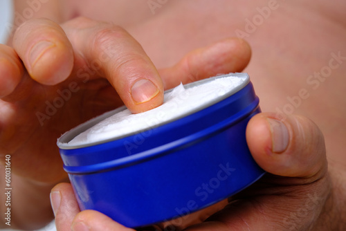 close-up of man smears nivea for men cream from new large round blue jar, skin care cosmetic, cosmetic anti-aging procedures, popular product, Frankfurt, Germany - June 2022 photo