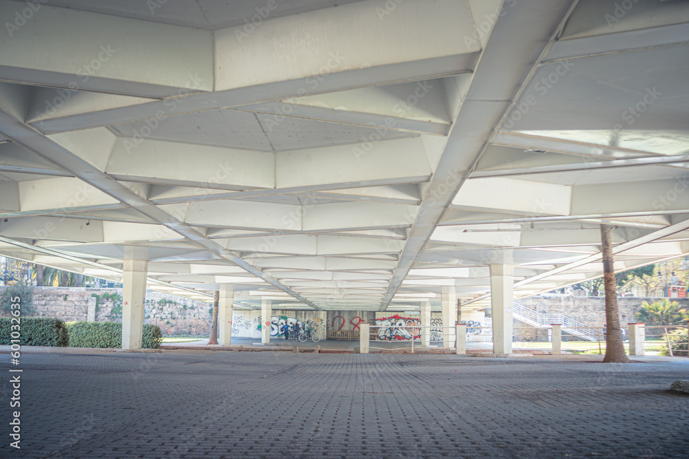 Urban white modern architecture under Valencia Flowers Bridge. Scene of metal steel structure with pure clear lines and concrete road pedestrian path. Automotive Puente de las Flores, wide angle view.