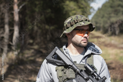 Private military mercenary with weapons in the forest, close-up photo.
