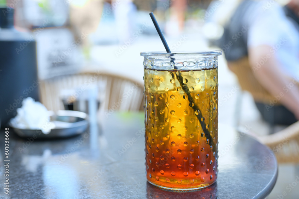 Refreshing iced tea with lemon syrup and a drinking straw in a glass in a street cafe in the summer, selected focus Refreshing iced tea with lemon syrup and a drinking straw in a glass in a street cafe in the summer, selected focus