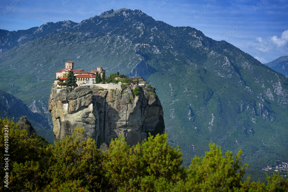 Monastery of the Holy Trinity built on the top of a rock in the Meteora complex near Kalambaka, famous tourism attraction in Greece, mountain landscape in the background, blue sky, copy space
