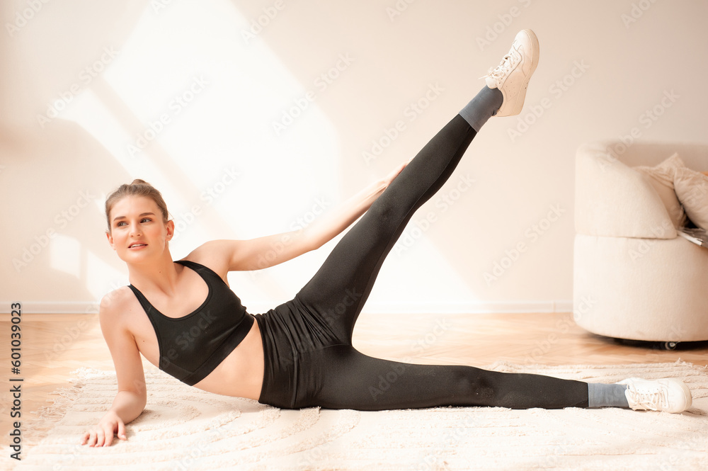 Obraz premium Young woman dressed in sportswear doing fitness exercises at home