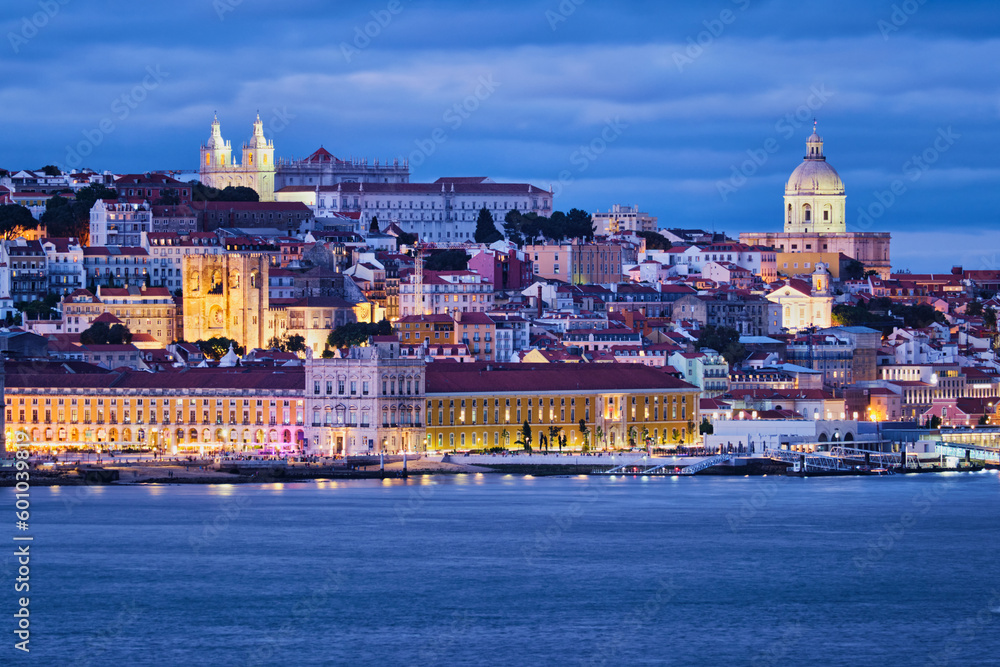 View of Lisbon over Tagus river Alfama district with National Pantheon and Monastery of St. Vincent with passing ferry boat from Almada with ferry in evening twilight. Lisbon, Portugal