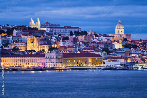 View of Lisbon over Tagus river Alfama district with National Pantheon and Monastery of St. Vincent with passing ferry boat from Almada with ferry in evening twilight. Lisbon, Portugal