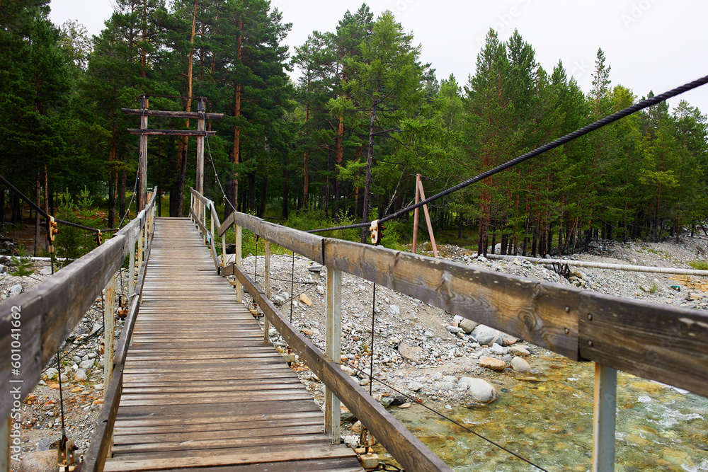 Suspended wooden bridge over the river. Beautiful summer landscape, forest. 