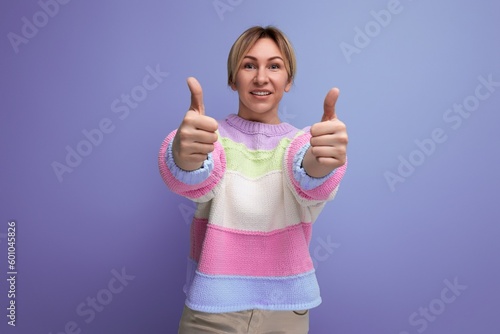 smiling blond young woman showing class on purple background with copy space