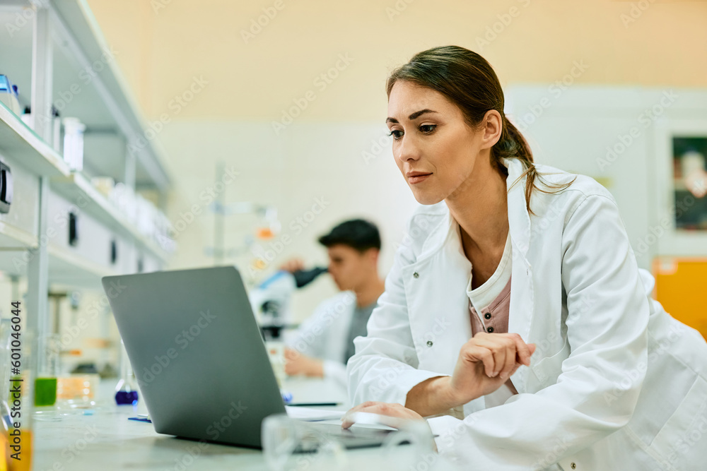 Young female scientist working on laptop in laboratory. Young female scientist working on laptop in laboratory.