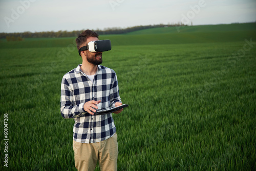 In virtual reality glasses. Handsome young man is on agricultural field © standret