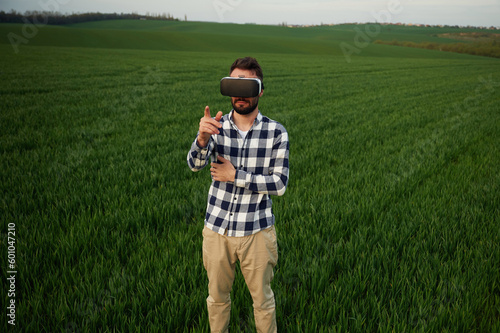 Playing game in VR glasses. Handsome young man is on agricultural field © standret