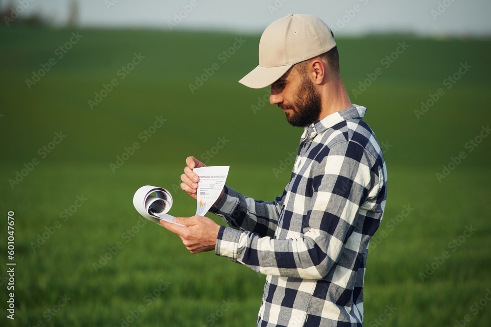Worker is reading the document. Handsome young man is on agricultural field Worker is reading the document. Handsome young man is on agricultural field