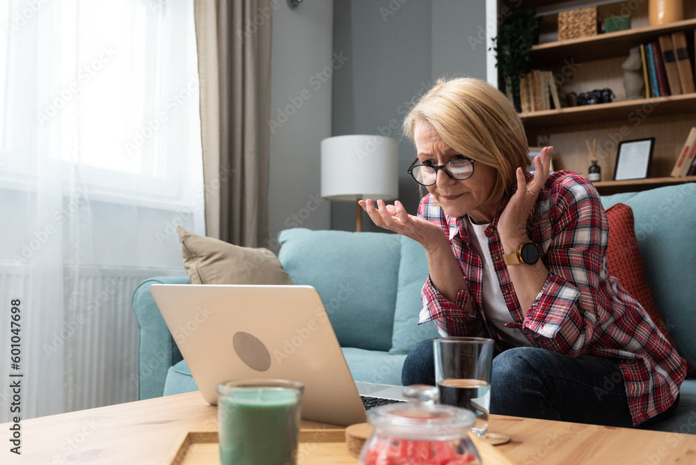 Worried middle-aged 70s lady sit on sofa in living room read negative unexpected news on laptop, anxious mature woman rest on couch feel distressed with unpleasant bad message on computer Worried middle-aged 70s lady sit on sofa in living room read negative unexpected news on laptop, anxious mature woman rest on couch feel distressed with unpleasant bad message on computer