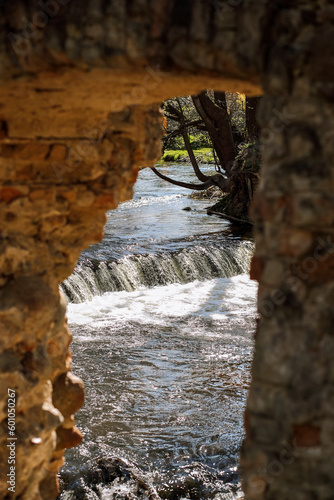 beautiful river waterfall in a wooded area and old ruins, vertical photo