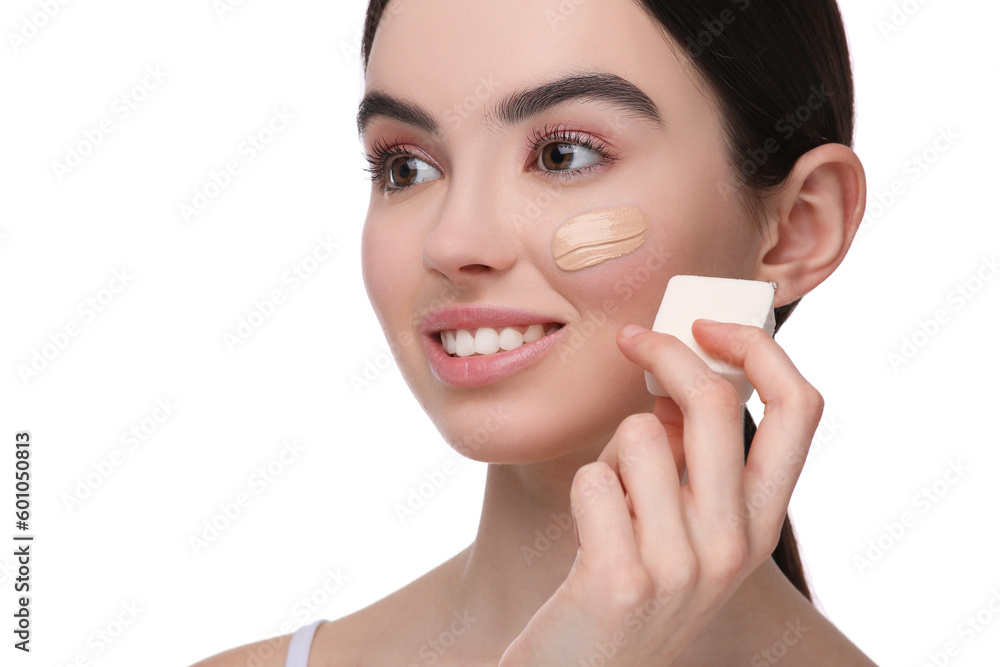 Teenage girl applying foundation on face with makeup sponge against white background Teenage girl applying foundation on face with makeup sponge against white background