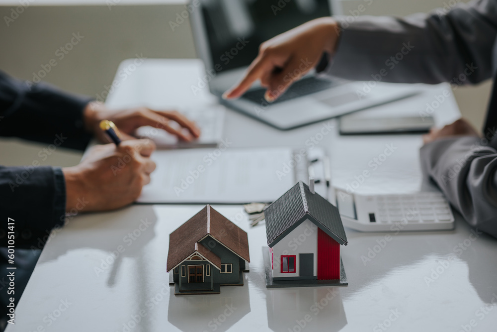 Fototapeta premium Businessman or real estate agent with house model laying down contract, having contract in place to protect it, signing little agreement form in office, keeping real estate, moving house or renting pr
