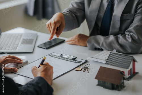 Fotografi Businessman or real estate agent with house model laying down contract, having c