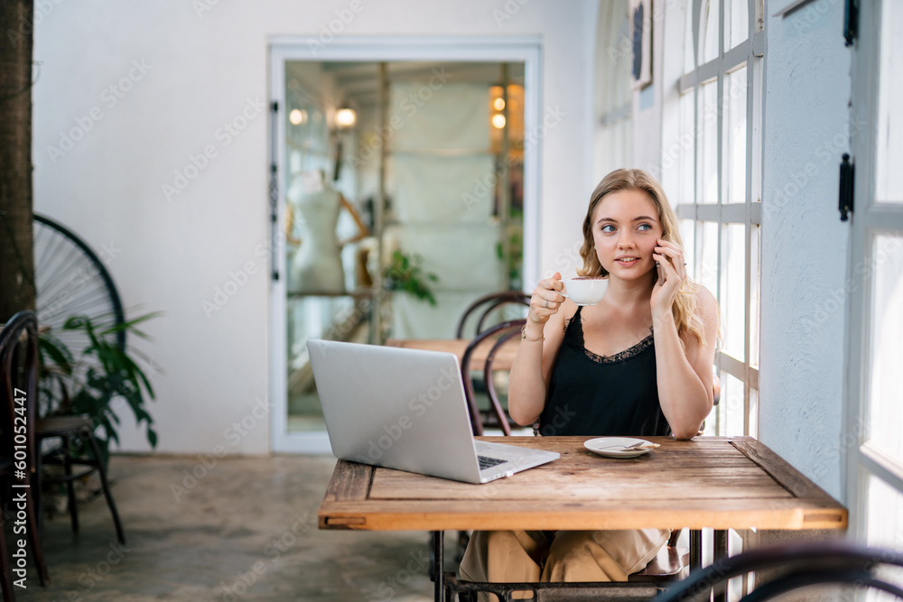 A woman looks out of the window while sitting happily drinking coffee on the desk in the morning. A woman looks out of the window while sitting happily drinking coffee on the desk in the morning.