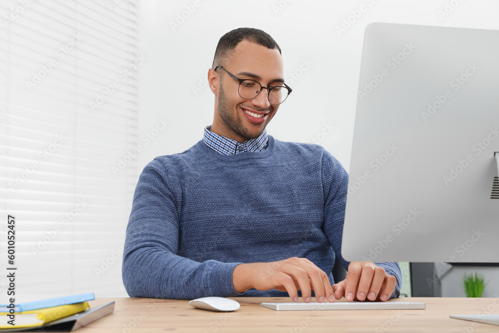 Happy young intern working with computer at table in modern office Happy young intern working with computer at table in modern office