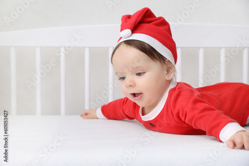 Cute baby wearing festive Christmas costume in crib. Space for text