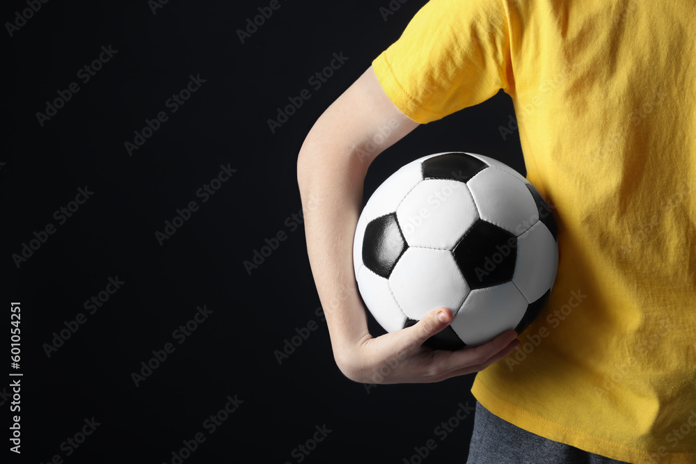 Teenage boy with soccer ball on black background, closeup. Space for text