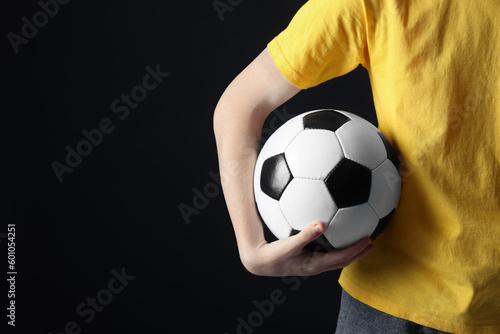 Teenage boy with soccer ball on black background, closeup. Space for text © New Africa