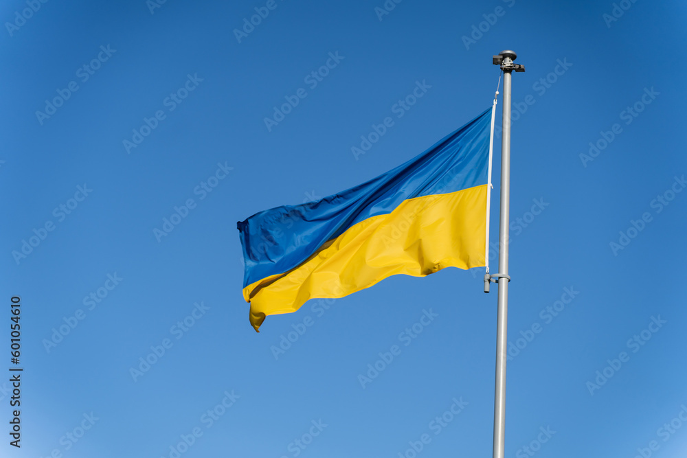 Blue-yellow Ukrainian flag flies against the background of clear blue sky Blue-yellow Ukrainian flag flies against the background of clear blue sky