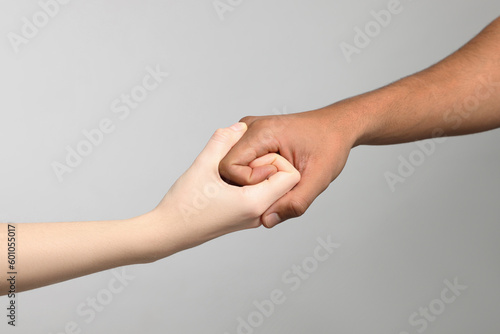 International relationships. People strongly joining hands on light grey background, closeup