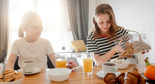 Girls sisters eat tasty breakfast together and filling plate with oat cereal meal. Female child kid and subling with musli food during morning nutrition