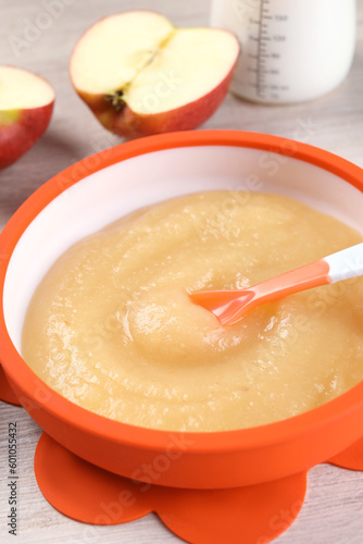 Healthy baby food. Bowl with delicious apple puree on white wooden table, closeup