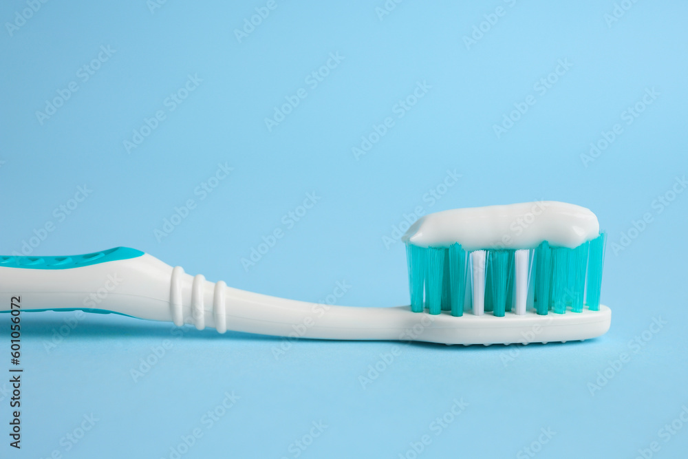Brush with toothpaste on light blue background, closeup Brush with toothpaste on light blue background, closeup