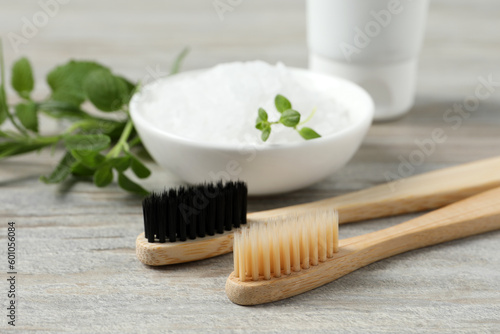 Toothbrushes  salt and green herbs on wooden table  closeup