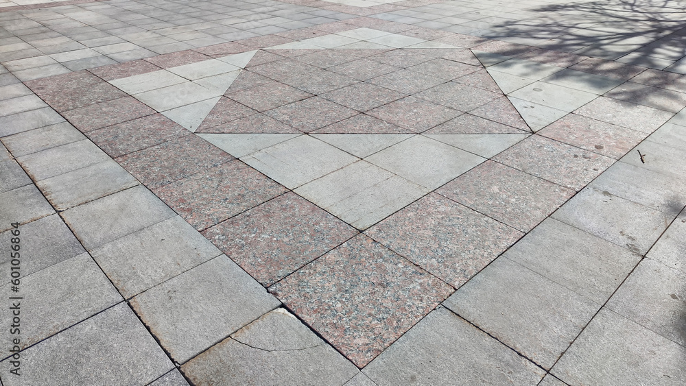 Fototapeta premium Gray tiles on the sidewalk in the city outdoors. Background and texture with lines and squares of tiles. Abstract frame, copy space, place for text