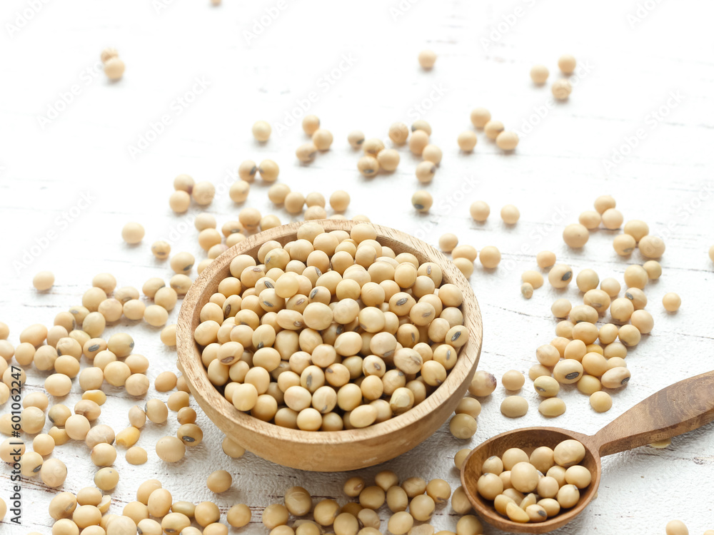 Soybean or soya bean in a wooden spoon on white wooden background. Used as a base for making soy sauce, tofu and tempeh Soybean or soya bean in a wooden spoon on white wooden background. Used as a base for making soy sauce, tofu and tempeh