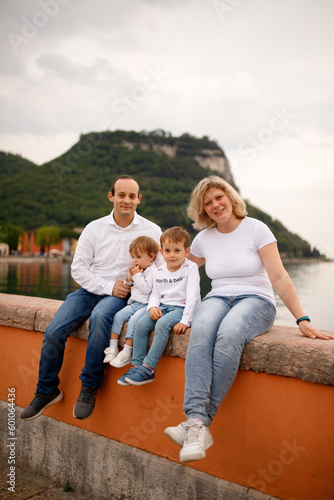 Happy family with toddler son and daughter sitting on the beach on the Italian Garda lake beach 