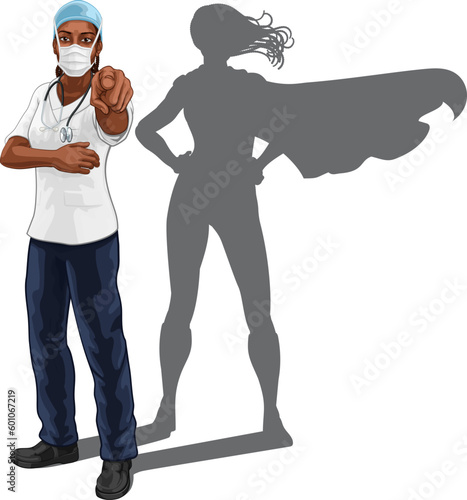 A super hero black woman doctor or nurse medical healthcare health professional in scrubs and mask PPE pointing. Revealed to be a superhero by her shadow.
