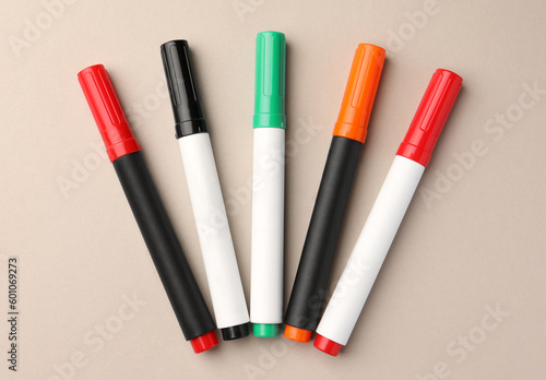 Bright color markers on beige background, flat lay