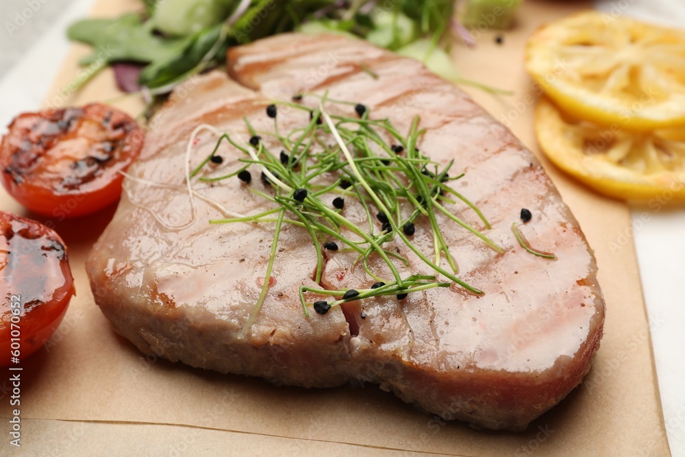Delicious tuna steak with microgreens on parchment paper, closeup Delicious tuna steak with microgreens on parchment paper, closeup